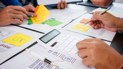 Close-up ux developers and ui designers use augmented reality to brainstorm on mobile app interface wireframe designs on modern office desks. Creative digital development office