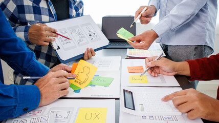 Close-up ux developers and ui designers use augmented reality to brainstorm on mobile app interface wireframe designs on modern office desks. Creative digital development office