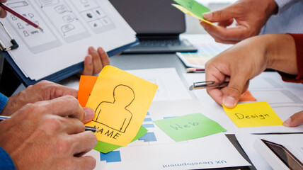 Close-up ux developers and ui designers use augmented reality to brainstorm on mobile app interface wireframe designs on modern office desks. Creative digital development office