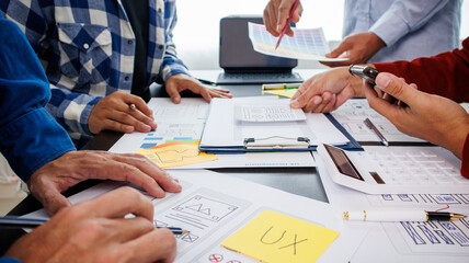 Close-up ux developers and ui designers use augmented reality to brainstorm on mobile app interface wireframe designs on modern office desks. Creative digital development office