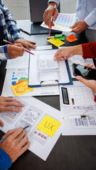 Close-up ux developers and ui designers use augmented reality to brainstorm on mobile app interface wireframe designs on modern office desks. Creative digital development office