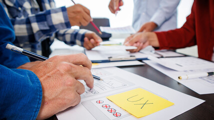 Close-up ux developers and ui designers use augmented reality to brainstorm on mobile app interface wireframe designs on modern office desks. Creative digital development office
