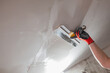 The master hand with a wide spatula applies white putty to the wall - leveling the wall into a plane for painting and wallpaper