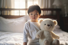 Boy Toddler, Dressed In White Pajamas, Gleefully Plays With A Stuffed Bear On The Bed, His Imagination Taking Flight As He Creates A World Of Adventure And Cuddles With His Fluffy Companion