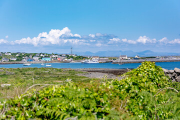 Beautiful blue view from behind bushes of the anchored boats in the harbor of Inishmore island, Galway