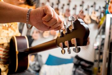 Wall Mural - Young musician tuning a classical guitar in a guitar shop