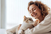 Beautiful Young Woman Is Holding A Cat And Smiling While Lying On The Bed At Home