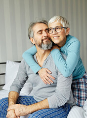 Wall Mural - couple senior bed woman man home wife husband love together elderly caucasian adult happy retirement mature male old bedroom smiling resting retired aged relaxation leisure lying relationship