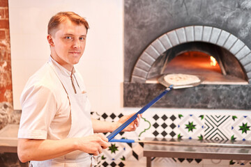 Wall Mural - Raw pizza ready to bake. The chef prepares pizza. boxes for food delivery on background. Neapolitan pizza from a wood-fired oven. 