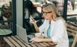 © Ilona - A woman eats a salad and works on a laptop in a cafe.
