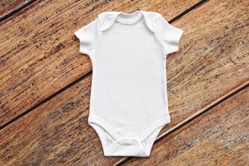 Wall Mural - Baby onesie flat lay on wooden background. Baby bodysuit mockup. Copy space for your design here. Top view. Flat Lay.