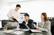 © Nuttapong punna - Group of young Asian business people discussing business plan at modern startup in creative business discussing work  office