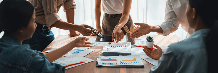 Leinwandbilder - Analyst team utilizing BI Fintech to analyze and pointing at financial dashboard paper office. Businesspeople examining report paper on table for business insight. Panorama shot. Scrutinize