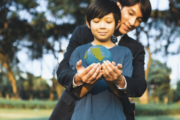 Asian boy and businessman holding planet Earth together as Earth day concept as corporate social responsible to make greener environmental protection for sustainable future generation. Gyre