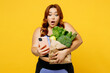 Young chubby overweight plus size big fat fit woman wear blue top warm up train hold bag with vegetables using mobile cell phone isolated on plain yellow background studio gym Workout sport concept