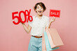 © ViDi Studio - Young surprised shocked woman wear casual clothes hold shopping paper package bags sale written text inscription 50 percent isolated on plain pink color background. Black Friday sale buy day concept.