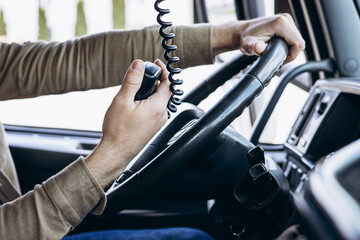 Wall Mural - Truck driver sitting in the cab of his lorry and using radio transmitter