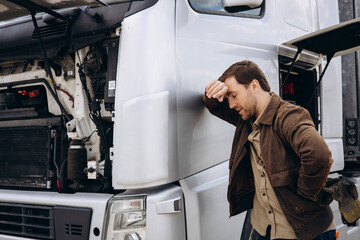 Canvas Print - Truck driver stopped on the road reparing his lorry