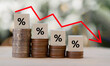 © Mongkol - Percentage sign on wooden cubes with Stack of coin bar chart and red graph trending downwards on nature background. Economy recession crisis, inflation, stagflation,business and financial loss concept