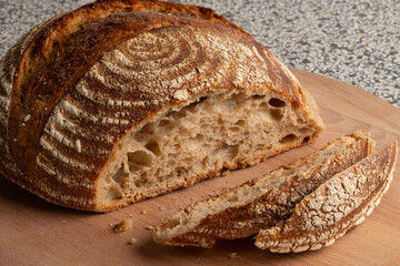 Wall Mural - Traditional homemade sourdough bread and slices on a cutting board close up