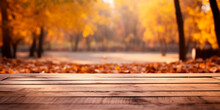 Wooden Empty Table In Front Of Blurred Autumn Park And Yellow Leaves. Platform/table For Product Demonstration.
