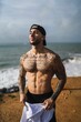 Topless Caucasian man from Spain with tattoos posing in a beach