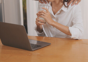 Handsome man sitting near his wife at kitchen. Family couple see social media, surf the web while sitting at kitchen table with generic laptop. Couple working with laptop at home