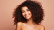© ckybe - Gorgeous African American woman showcases flawless, radiant skin against a beige backdrop. A captivating smile graces Afro beauty with luscious, curly black hair.