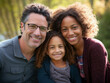 Casual close-up portrait of mixed-race family of white father, black mother, and biracial daughter.  All are looking at the camera and smiling.