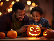 Closeup of black father and son carving a jack-o-lantern out of a pumpkin for Halloween.  They are laughing and having fun together.