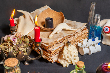 Wall Mural - Mystic occult witchcraft background with witch craft tools on old yellow parchment grimoire weathered pages, magic ritual. Halloween theme, goat jaw bones, black candles and raven toe for spells.