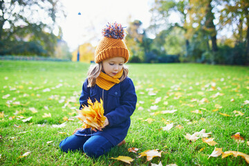 Wall Mural - Adorable preschooler girl enjoying nice and sunny autumn day outdoors