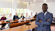 © JackF - Portrait of successful african american businessman in front of team of businessmen in a meeting room