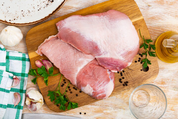 Fresh raw pork secreto fillet, special cut of Iberian pig meat and condiments prepared for roasting on wooden cutting board