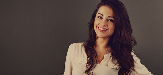 Wall Mural - Beautiful business toothy enjoying laughing woman with long brown healthy curly hair style in white shirt clothing. Closeup