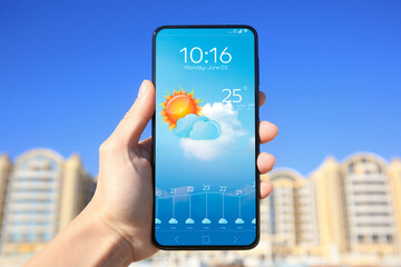 Wall Mural - man using weather forecast app on smartphone outdoors on sunny day, closeup. data and illustration o