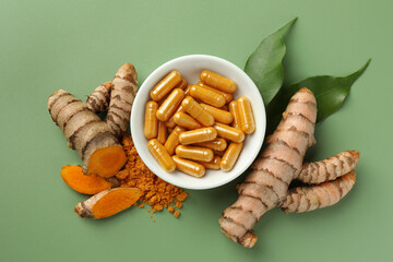 Wall Mural - Aromatic turmeric powder, pills and raw roots on green background, flat lay