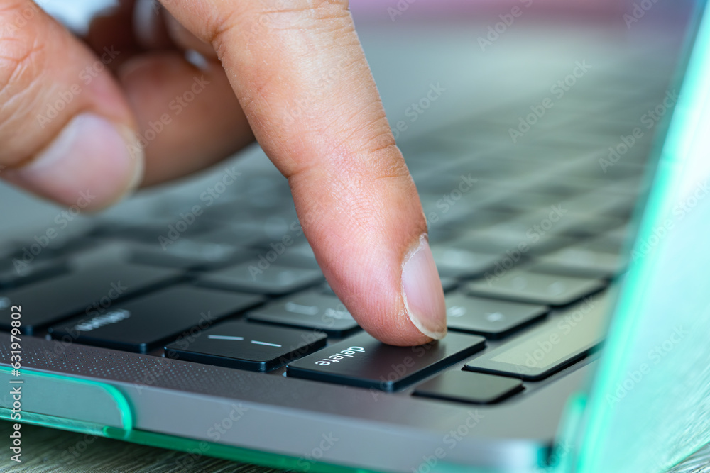 Finger of the computer user, he presses the delete button on the ...