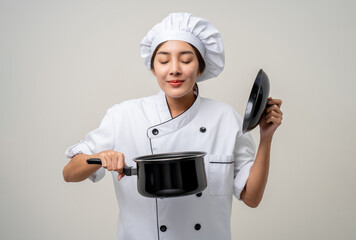 Wall Mural - Young beautiful asian woman chef in uniform holding soup pot ladle utensils cooking in the kitchen various gesture menu good taste on isolated. Cooking woman chef people in kitchen restaurant