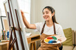 © Chanakon - Asian woman artist working on painting with brush and variant acrylic color. Female artist painter on canvas in creative studio as art concept