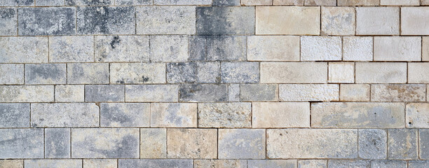 Wall Mural - wide impressive old castle stone wall. panoramic stone wall background for design with copy space.