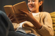 © Chanakon - Close up female hands holding book turning the page. Young woman sitting on cozey couch sofa reading book in living room with warm light at night. People female stay home part time relax at home.