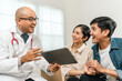 © Chanakon - Asian family discussing fertility with a pediatrician. Young couple patients in fertility clinic consulting about IVF or IUI with doctor. Couple relationship therapy with a counselor