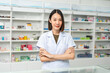 © Chanakon - Beautiful asian woman pharmacist checks inventory of medicine in pharmacy drugstore. Professional Female Pharmacist wearing uniform standing near drugs shelves counter