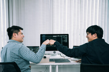 Wall Mural - asian employee software developers celebrate success project by fist bump in office room.