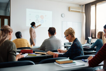 smiling mature woman takes notes during education training class.