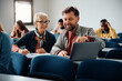 © Drazen - Adult students cooperate while using laptop and studying together in classroom