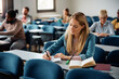 © Drazen - Mid adult woman writes in notebook while attending class at university