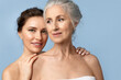 © deniskomarov - Tender smiling woman  hugs her elderly mother by the shoulders. Beauty portrait of beautiful women of two generations