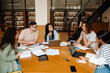 © Drobot Dean - Group of multiethnic students talking while studying together in library